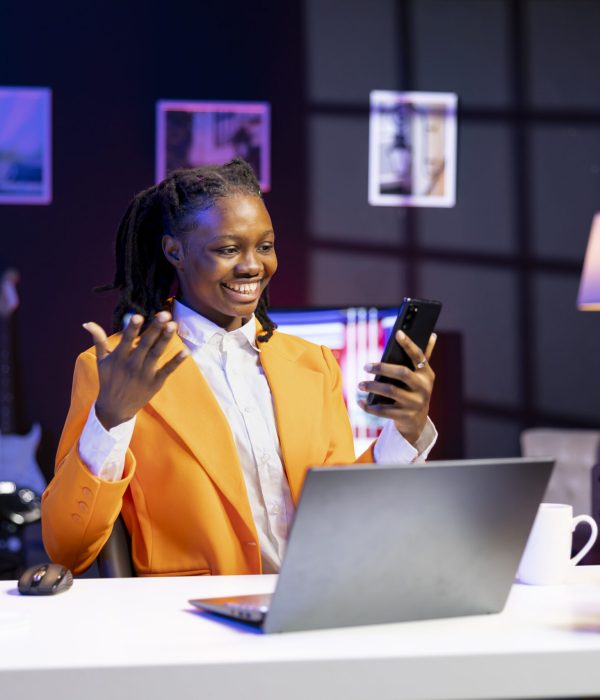 African american woman relaxing in apartment, texting friends on cellphone, enjoying leisure time. Smiling remote worker taking break to talk with mates on internet using phone